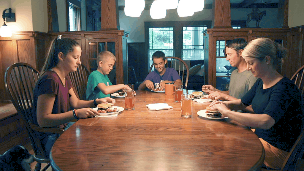 photo of Logan Rohr, founder of Honeytown Meats, and his family around the dinner table.